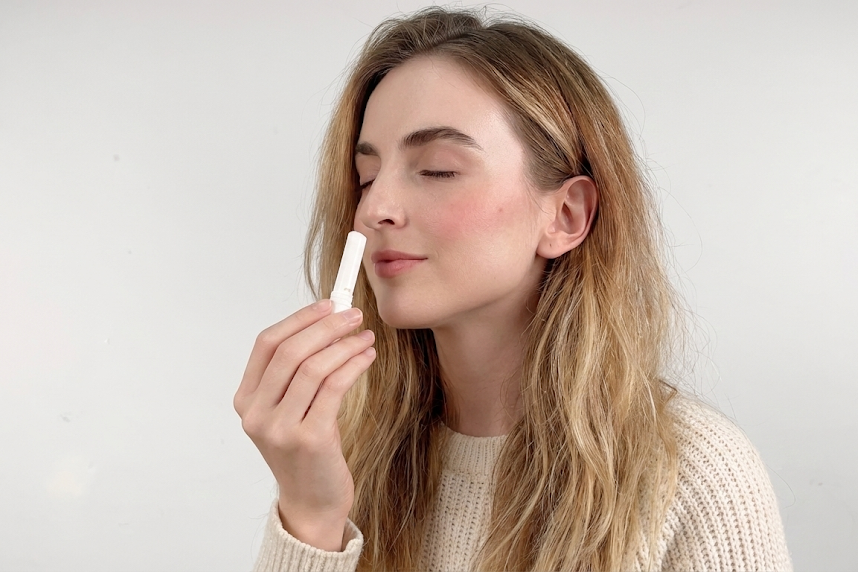 Woman inhaling nasal stick with a neutral background