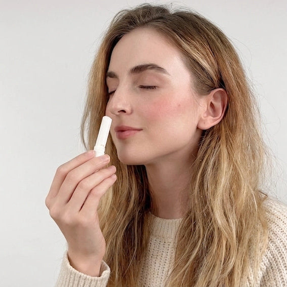 Woman inhaling nasal stick with a neutral background